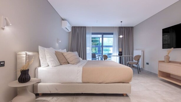 A modern bedroom with a large bed, a desk, and a TV.