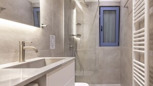 A modern bathroom with a shower, toilet, and sink.