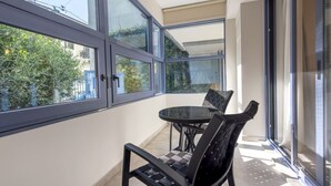 A balcony with a glass door, a round table, and two chairs.