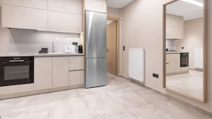 A modern kitchen with a built-in oven, a stainless steel refrigerator, and a large mirror reflecting the space.