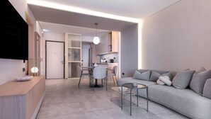 Una sala de estar moderna con un sofá gris, una mesa de centro y un comedor con sillas y una mesa.