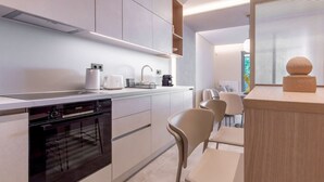 Una cocina moderna con electrodomésticos integrados, un comedor con sillas y una ventana con persianas.