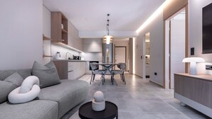A modern living room with a grey sofa, a black coffee table, and a dining area with a table and chairs. - Phaedrus Living: Athens Luxury Residences Sands (Athina)