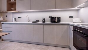 A modern kitchen with grey cabinets, a white countertop, and a built-in oven. - Phaedrus Living: Athens Luxury Residences Sands (Athina)