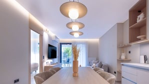 A modern kitchen with a wooden dining table, built-in cabinets, and pendant lighting. - Phaedrus Living: Athens Luxury Residences Sands (Athina)