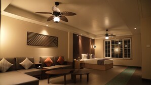 A modern hotel room with a sofa, a bed, a ceiling fan, and a large window. - The Solitaire bliss (Tinsukia)