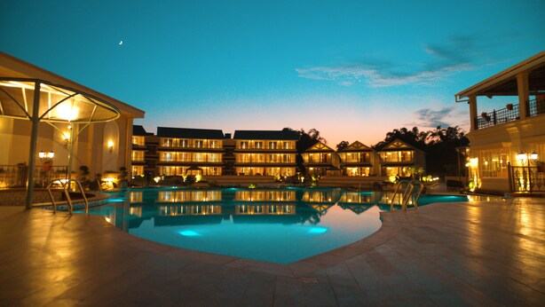 A hotel with a swimming pool, multiple balconies, and a night sky with a visible moon. - The Solitaire bliss (Tinsukia)