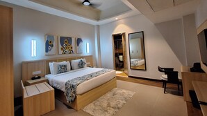 A modern bedroom with a bed, bedside tables, a desk, a mirror, and artwork on the wall. - The Solitaire bliss (Tinsukia)