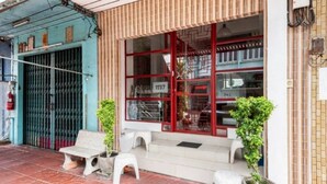 A building with a red-framed window, a metal gate, and a tiled floor. - 1137 Hostel (Bangkok)