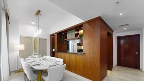 A modern dining area with a round table set for six, white chairs, a pendant light, and a wooden accent wall. - Exclusive Duplex Villa w Panoramic Terrace Overlooking Burj Khalifa (Dubai)