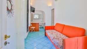 Un espacio habitable compacto con sofá, una kitchenette pequeña y una zona de comedor.