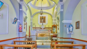 Interior de iglesia con bancas de madera, un altar central y estatuas religiosas.