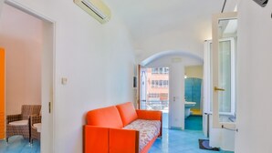 A compact living space with a sofa, a dining table, and a view of the outside. - Appartamento a Amalfi ID 3059 (Amalfi)