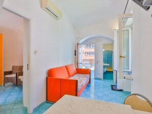 Un espacio habitable compacto con sofá, mesa de comedor y vista al exterior.