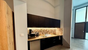 A modern kitchen with dark cabinets, a stone backsplash, and a dishwasher. - Thissio Luxury Apartment (Athens)