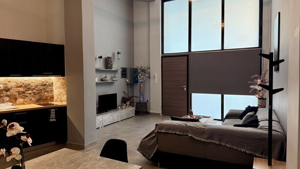 A modern bedroom with a large window, a bed, a desk, and a TV. - Thissio Luxury Apartment (Athens)