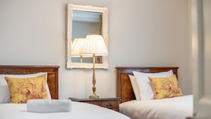 Een hotelkamer met twee bedden, een nachtkastje, een lamp en een spiegel.