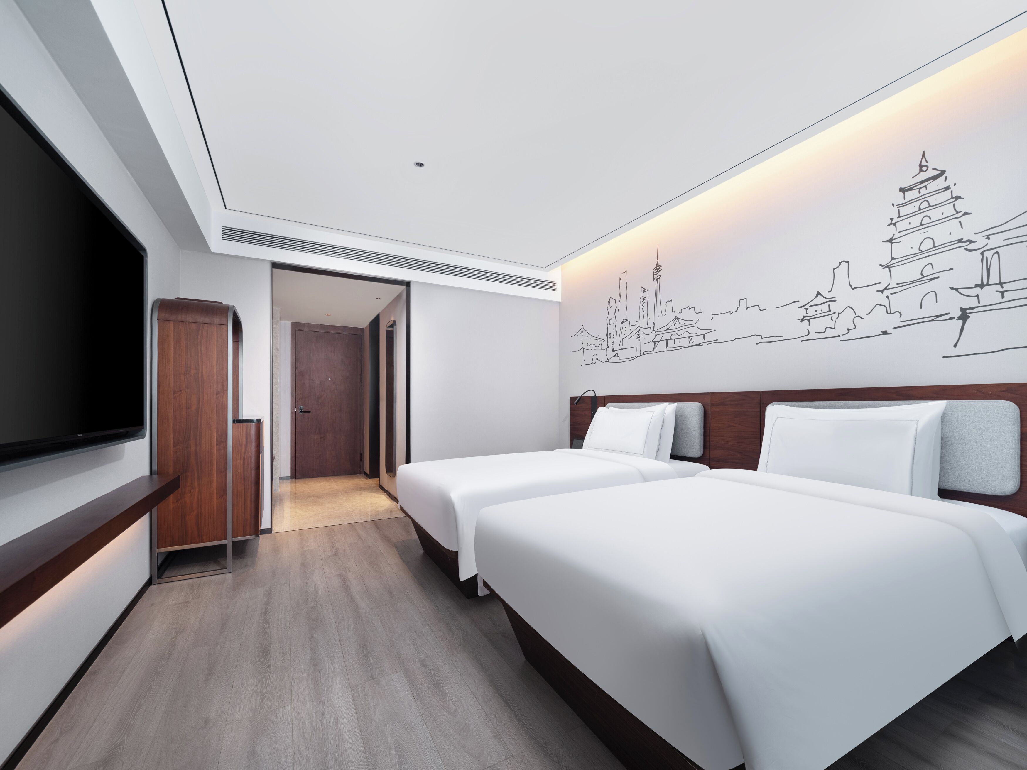 A hotel room with two beds, a TV, a wooden wardrobe, and a cityscape wall art.