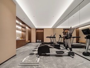 Un gimnasio moderno con equipo de ejercicio, una zona de recepción y un espejo grande.