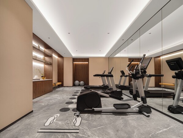 A modern gym with exercise equipment, a reception area, and a mirrored wall. - UrCove by Hyatt Xi'an Great Tang All Day Mall (Xi'an)