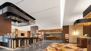 Eine moderne Hotelhalle mit Barbereich, Sitzgelegenheiten und einem gemusterten Teppich.
