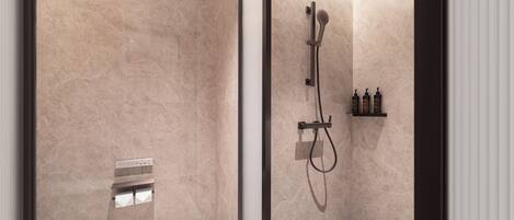 Un baño moderno con cabina de ducha de vidrio, inodoro y repisa con artículos de aseo.