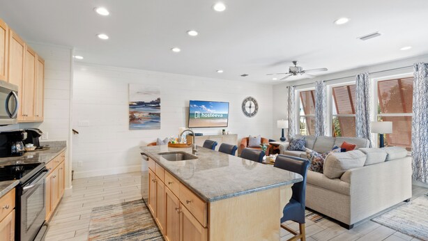 A modern kitchen with a central island, wooden cabinets, and a built-in oven. - Drift Away (Gulf Shores)
