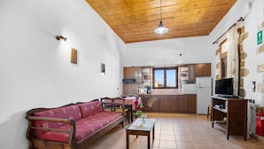A living room with a wooden ceiling, a sofa, a coffee table, and a television. - Countryside Apartment 2 With Shared Swimming Pool (Kissamos)
