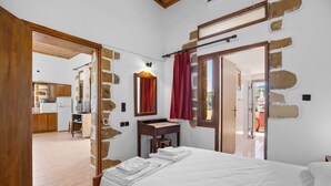 A bedroom with a bed, a wooden desk, a mirror, and a red curtain. - Countryside Apartment 2 With Shared Swimming Pool (Kissamos)