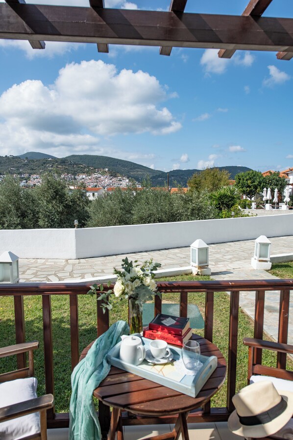 Una terraza con una mesa para dos, con vistas a un pueblo y colinas.
