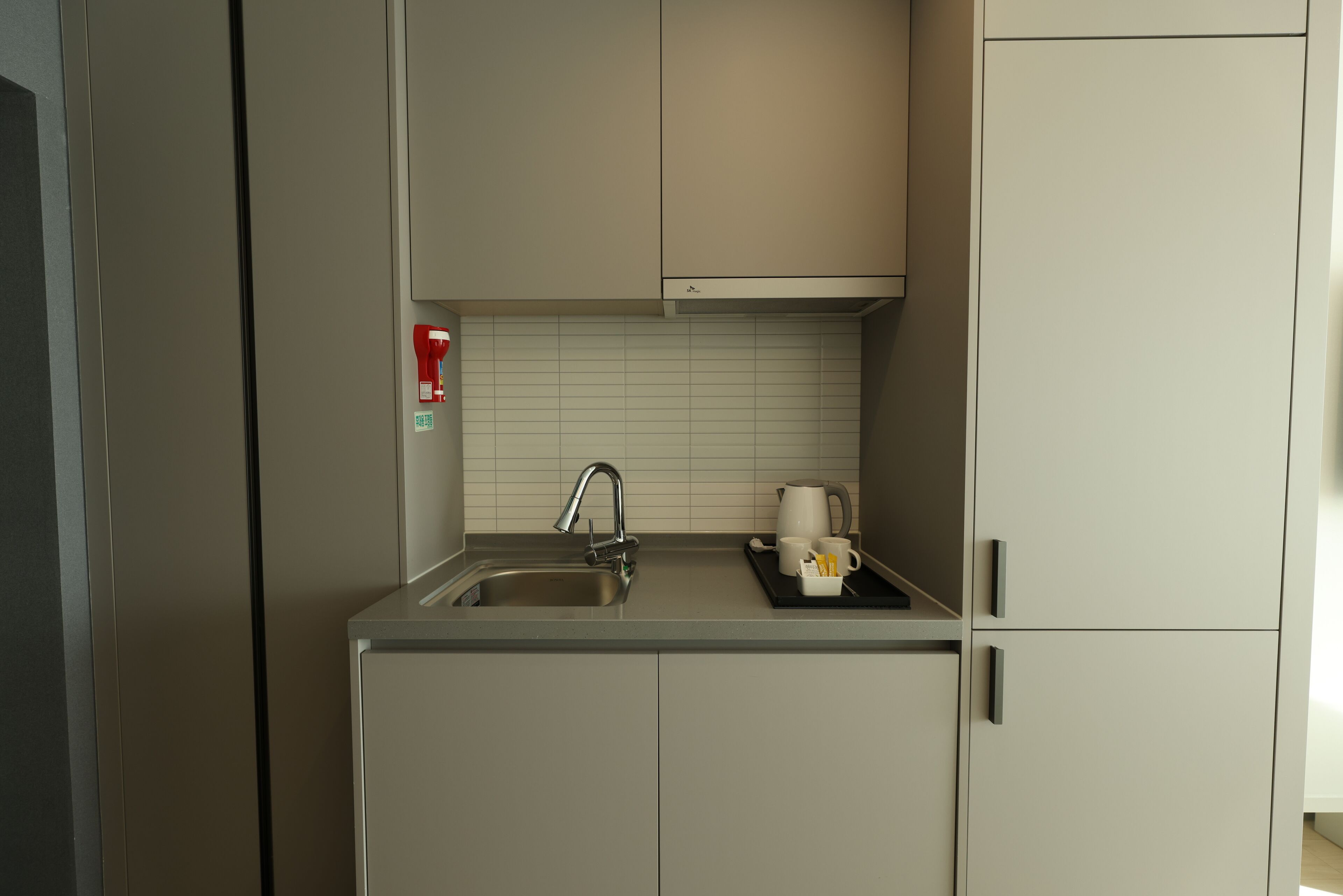 Una cocina compacta con un lavamanos, un grifo y una encimera.
