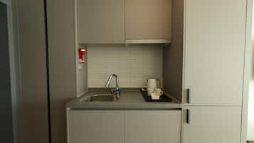 Una cocina compacta con un lavamanos, un grifo y una encimera.