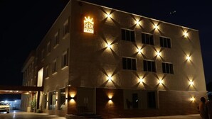 Ett hotell med en tydlig skylt som visar texten ”RHR GRAND”, många fönster och en väl upplyst entré.