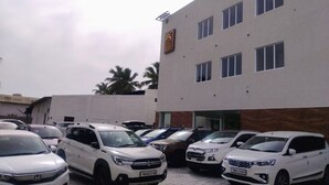En parkeringsplats med flera vita terrängbilar parkerade framför en byggnad där det finns en skylt som tyder på att det är ett hotell eller någon form av företag.