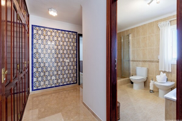 Ein Badezimmer mit zwei Toiletten, einer Dusche und einem Waschbecken.
