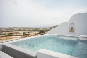 A pool with a view of a landscape and a white building with a small window. - Apleton Villas Paros (Paros)