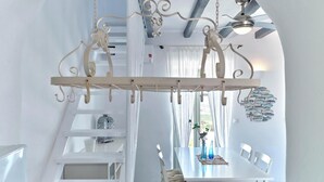 A dining area with a white table, chairs, and a decorative ceiling fan. - Apleton Villas Paros (Paros)