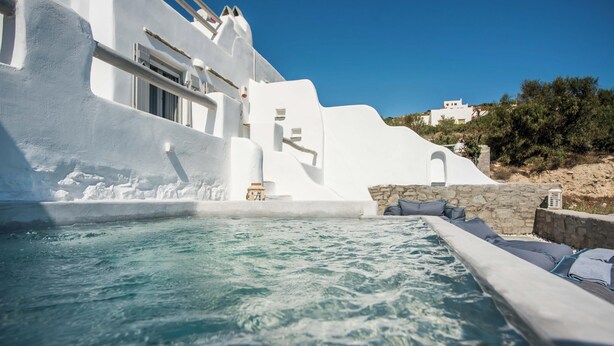 A white building with a pool, stone walls, and a clear blue sky. - Apleton Villas Paros (Paros)