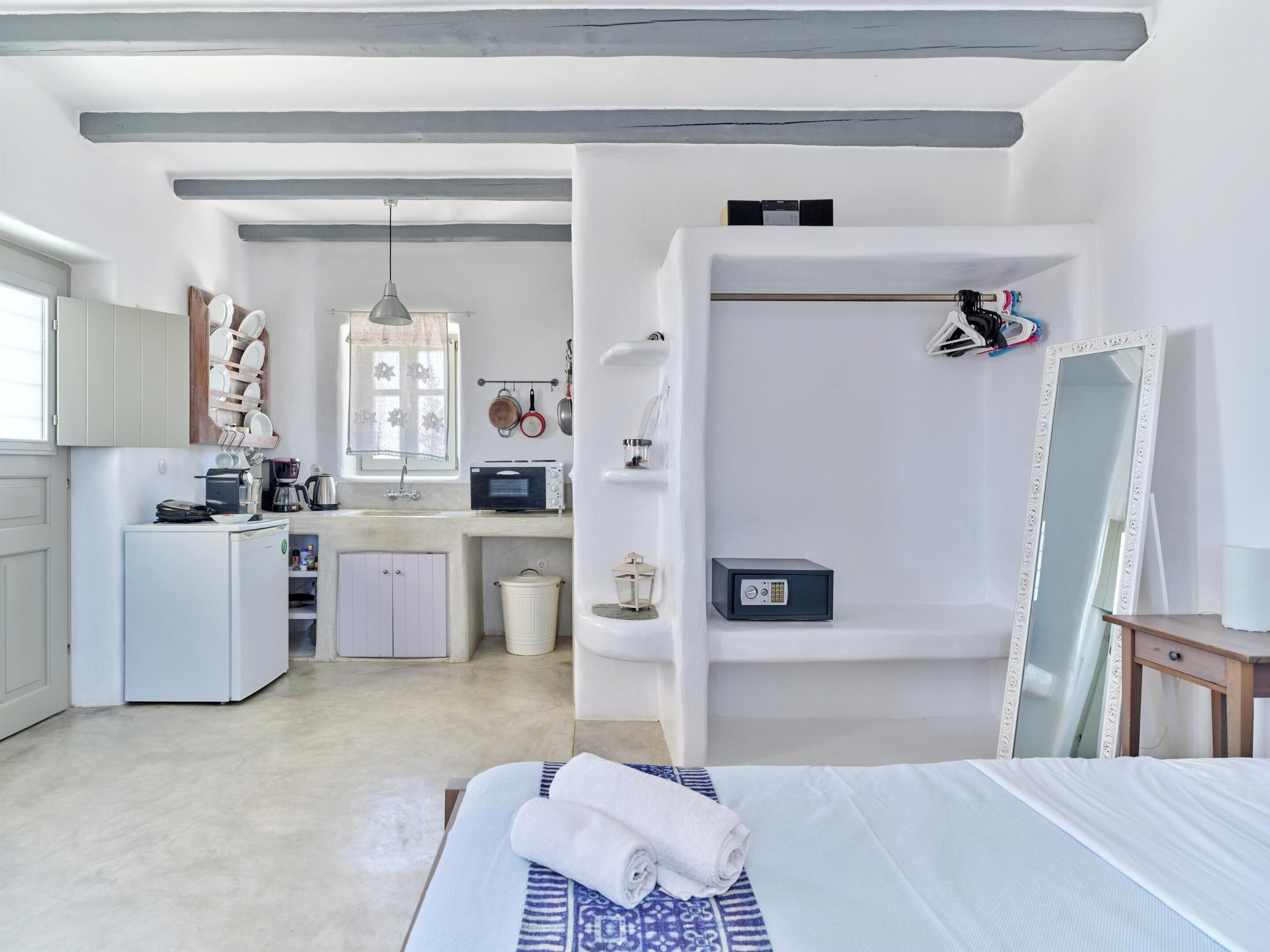 A compact bedroom with a bed, a bedside table, a wardrobe, and a small kitchenette.
