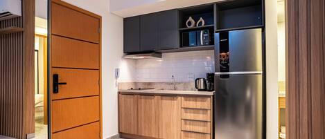 A modern kitchen with wooden cabinets, a stainless steel refrigerator, and a microwave.