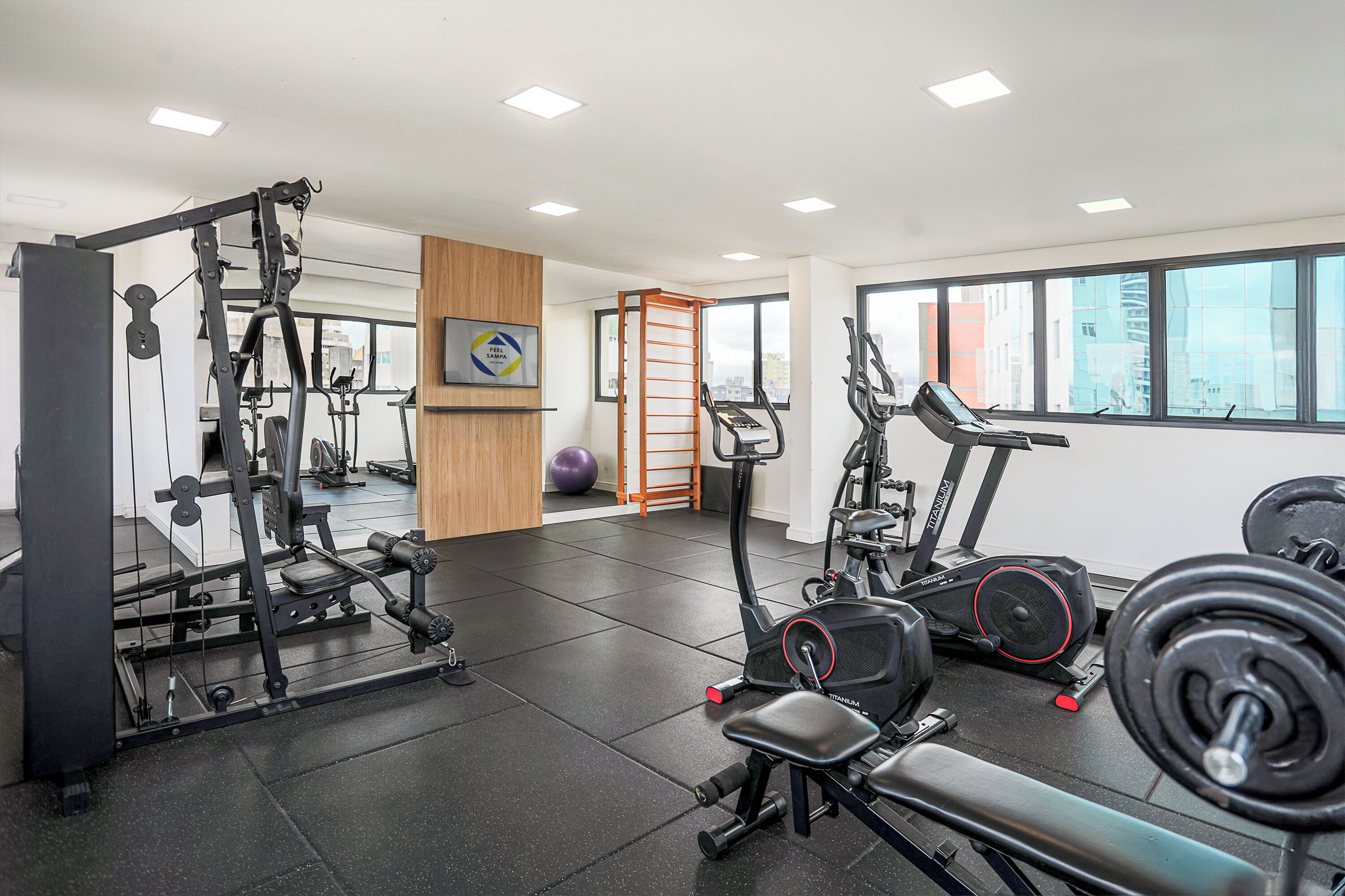 Una palestra con diverse attrezzature per esercizi, un tapis roulant e una panca per pesi.