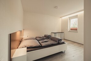 Une chambre à coucher moderne avec un lit, des tables de chevet, une fenêtre et une petite table.