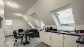 Egy modern konyha étkezővel, ahol egy tetőablak, egy fekete kanapé és egy kávéfőző található.