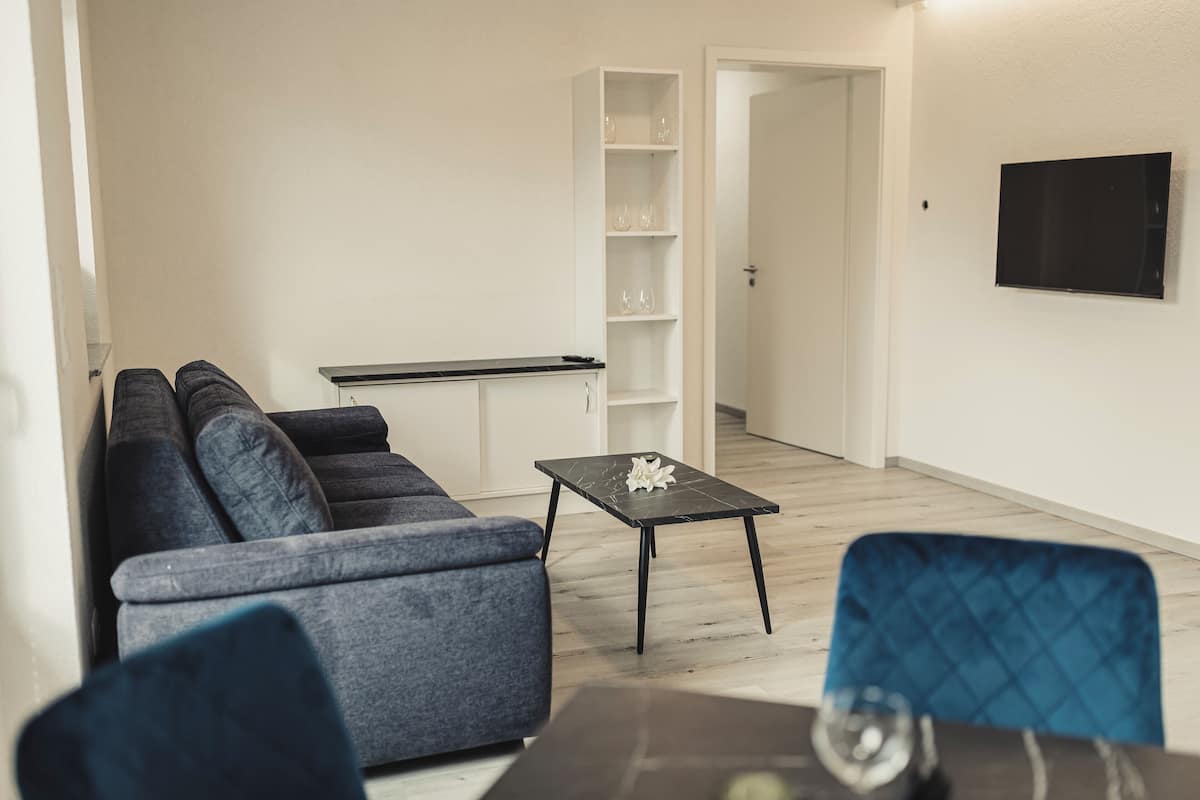 A living room with a sofa, a coffee table, and a dining table.