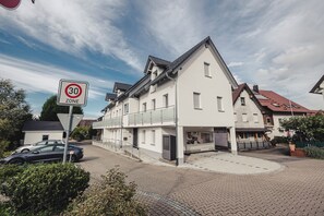 Un immeuble résidentiel avec un panneau indiquant une limite de vitesse de 30, une entrée fermée par un portail et une allée pavée.