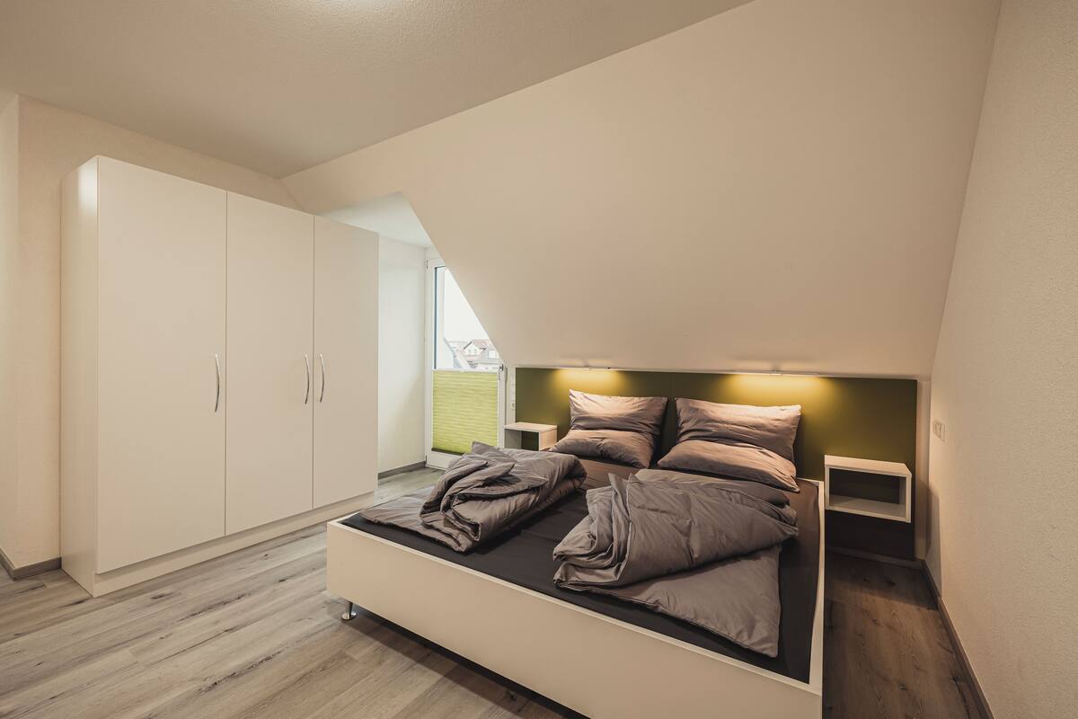 A bedroom with a bed, a wardrobe, and a window.