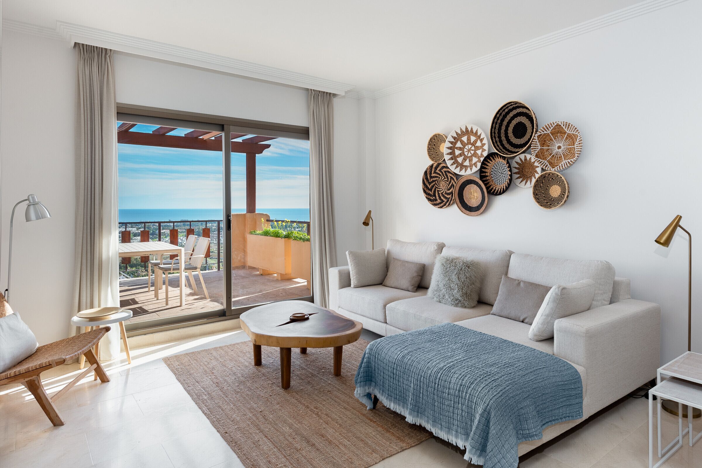 A modern living room with a sofa, a coffee table, and a view of the outdoors through a large sliding door.