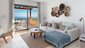 Ein modernes Wohnzimmer mit einer Couch, einem Couchtisch und Blick ins Freie durch eine große Schiebetür.