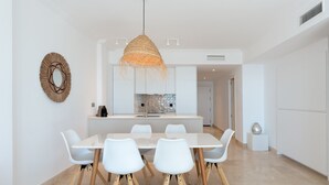 A modern dining area with a white table and chairs, a woven pendant light, and a decorative wall piece. - Premium Penthouse with Unmatched Views (Benahavís)