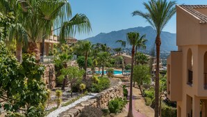 A resort with a pool, palm trees, and mountains in the background. - Premium Penthouse with Unmatched Views (Benahavís)